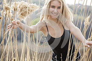 Outdoor fashion photo of young beautiful lady in autumn landscape with dry flowers