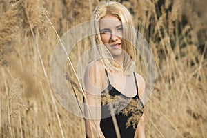 Outdoor fashion photo of young beautiful lady in autumn landscape with dry flowers