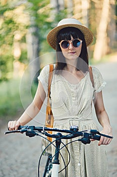 Outdoor portrait of attractive young brunette in a hat on a bicycle.