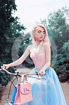 Outdoor fashion portrait of a beautiful blonde girl cycling in the park