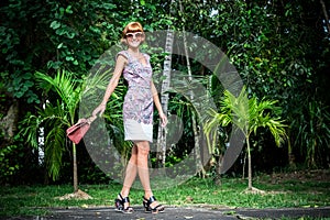 Outdoor fashion portrait of glamour sensual young stylish lady in sunglasses with luxury handmade snakeskin python bag