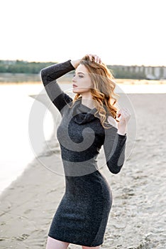 Outdoor fashion portrait of pretty young sensual woman posing in black dress on the beach