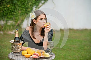 Outdoor fashion portrait sexy woman relaxing near summer garden eating orange, summer tropical fruits. Beautiful woman