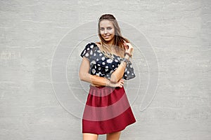 Outdoor fashion portrait of stylish girl posing against grey wall - copy space