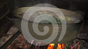 An outdoor fireplace fire oven with fire burning, built from bricks and stones. Cooking food in the oven on an open fire