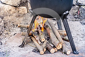 Outdoor fireplace under a cast-iron pot with roasts. barbeque party