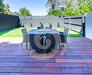 Outdoor furniture - dining table with chairs on a wooden deck at townhouse back yard.