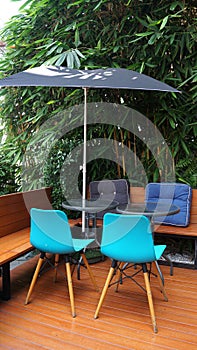 Outdoor furniture set with Blue plastic chair and wooden legs on timber deck