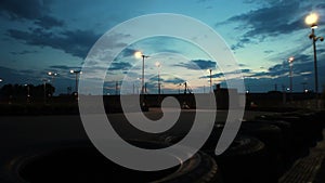 Outdoor go-kart track with cars passing under dark blue evening sky, time-lapse