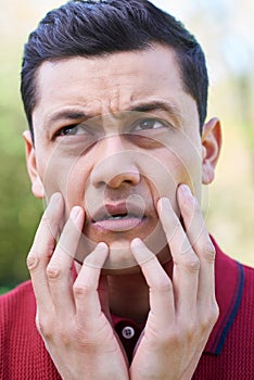 Outdoor Head And Shoulder Portrait Of Worried Young Man