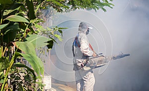 Outdoor healthcare worker using fogging machine spraying chemical to eliminate mosquitoes and prevent dengue fever at slum area