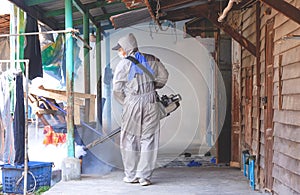 Outdoor healthcare worker using Fogging Machine Spraying chemical to Removal Mosquitoes in slum area