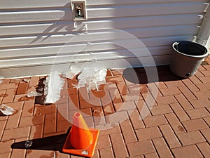 Outdoor hose spigot with ice and red bricks in winter