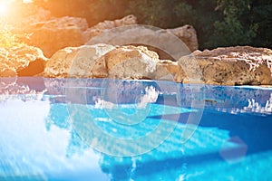 Outdoor inground residential swimming pool in backyard with hot tub. Sun flare