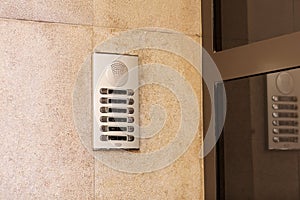 Outdoor intercom outside a residential building with empty name tag cards. Silver modern doorbells with blank nameplates