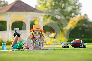 Outdoor kid play and draw craft artwork homework. School boy in park outdoor doing school homework. Child kid writing in