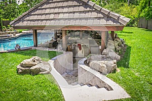 Outdoor kitchen sunken into ground by swimming pool to create a swim-up bar with concrete steps leading down