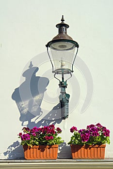 Outdoor lantern on white wall, pots with flowers