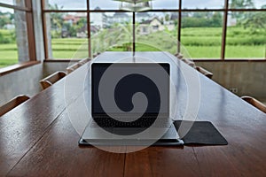 An outdoor laptop lies on a wooden table in an internet cafe. Without people