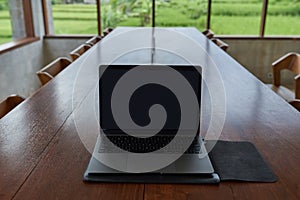 An outdoor laptop lies on a wooden table in an internet cafe. Without people