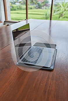 An outdoor laptop lies on a wooden table in an internet cafe. Without people