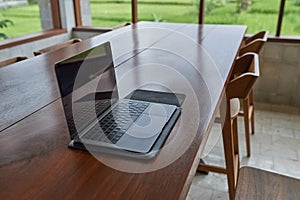 An outdoor laptop lies on a wooden table in an internet cafe. Without people