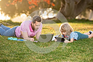 Outdoor learning. Blogging. Happy father using laptop relax with schooler son holding laptop. Childhood and parenthood