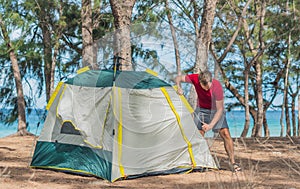 Outdoor lifestyle eco sport tourist put up set up green campsite, summer forest near lazur sea. Man assembling study