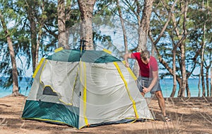 Outdoor lifestyle eco sport tourist put up set up green campsite, summer forest near lazur sea. Man assembling study photo