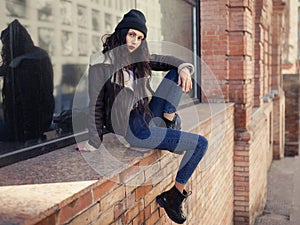 Outdoor lifestyle fashion portrait of pretty young girl, wearing in hipster swag grunge style on urban background. Wearing hat and