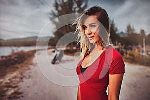 Outdoor lifestyle portrait of young sexy woman in red bikini near her a vintage custom motorcycle