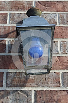 An outdoor light fixture with a blue light bulb