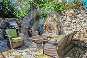 Outdoor living - rock wall and built-in outdoor fireplace built around a corner tree with wicker furniture and an electric outdoor