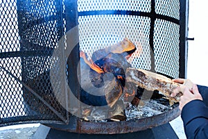 Outdoor metallic fireplace in winter season charged with firewood, in the burning process