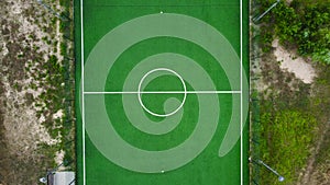Outdoor mini football field located among meadow, vertical aerial view