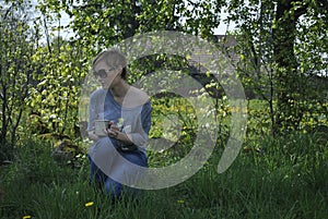 Young blond woman sitting in the garden in the sunny day photo