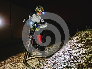 Outdoor orienteering extreme bike race in night. Woman check