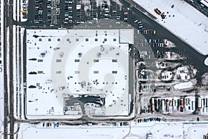 Outdoor parking lot with many cars near supermarket in winter. aerial top view