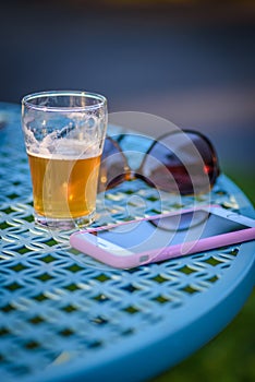 Outdoor patio table with mobile phone sunglasses and beer flight glass