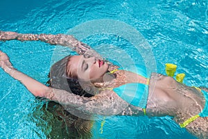 Outdoor photo of beautiful woman wears luxurious bikini swimsuit, posing in the swimming pool. Sexy female model relax