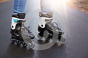 Outdoor picture of roller blades, being testified by unknown person, being in middle of road, tool for active lifestyle, using for