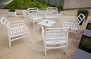 Outdoor plastic furniture in garden patio, white chairs with table in cafe, summer time