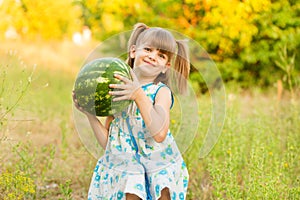 Outdoor portait of happy smilling little girl with watermelon in summertime