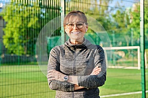 Outdoor portrait of active smiling middle aged woman looking at camera