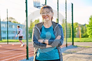 Outdoor portrait of active smiling middle aged woman looking at camera