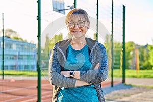 Outdoor portrait of active smiling middle aged woman looking at camera