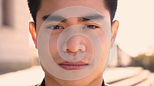 Outdoor portrait of an Asian man looking at the camera with a serious face and intense look. Close up of a