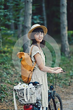 Outdoor portrait of attractive young brunette in a hat on a bicycle.