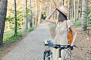 Outdoor portrait of attractive young brunette in a hat on a bicycle.