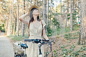 Outdoor portrait of attractive young brunette in a hat on a bicycle.